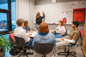 5 elevar i et klasserom og ein lærar som skriv på ei tavle
