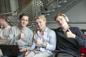 Tre gutar sit tett saman og held opp tommelen